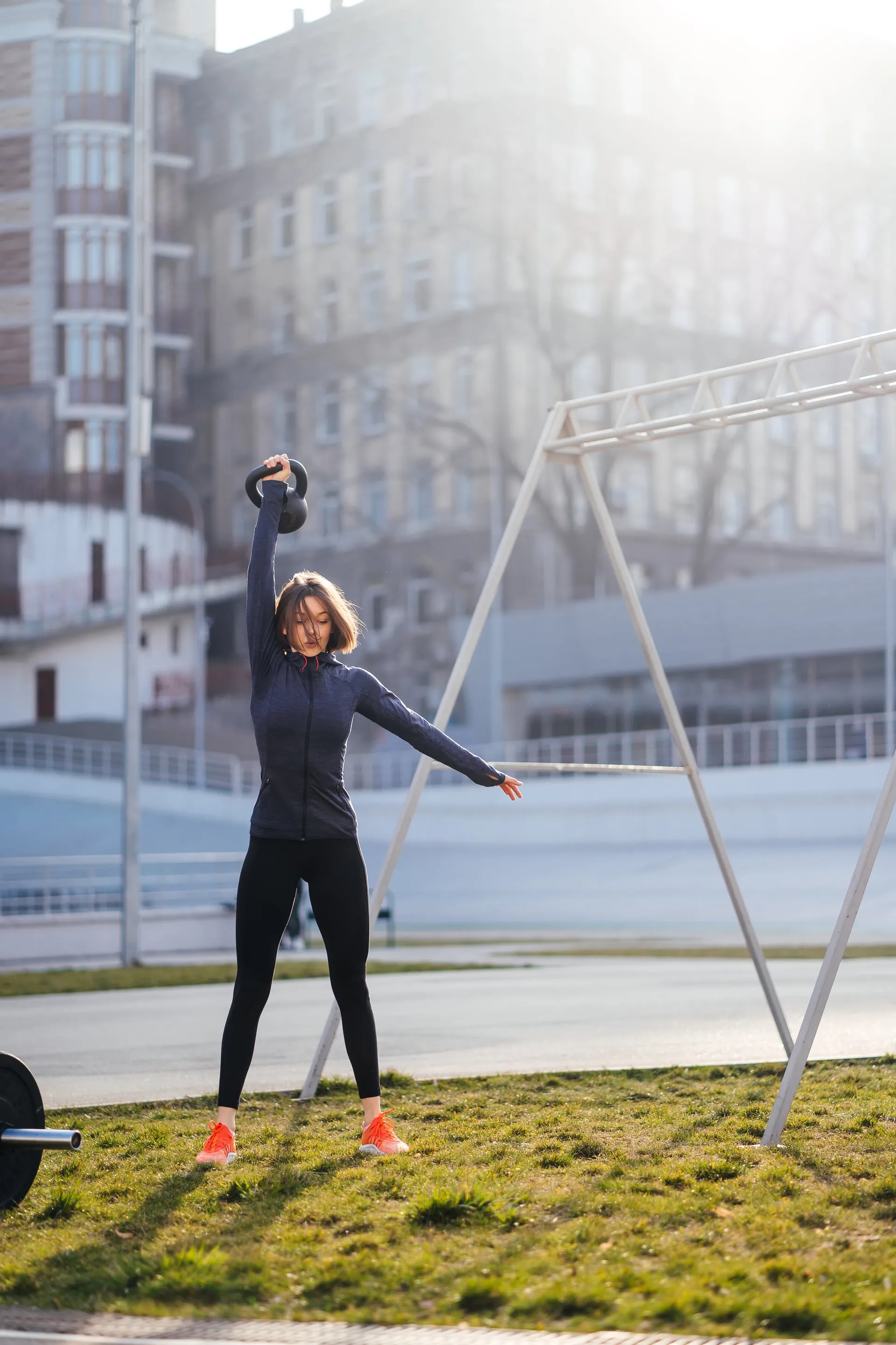 Mujer joven entrenando con kettlebell al aire libre en un ejercicio funcional
