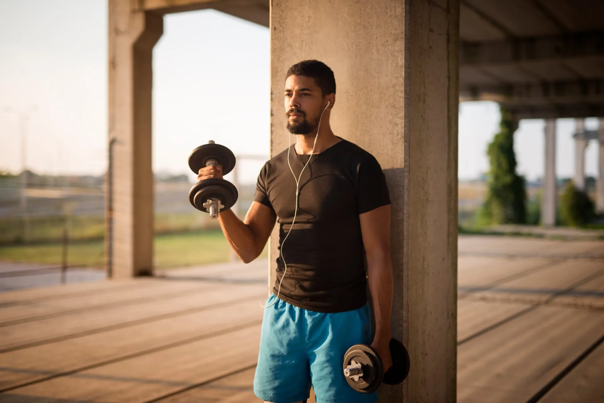 Hombre entrenando con mancuernas en exterior al atardecer